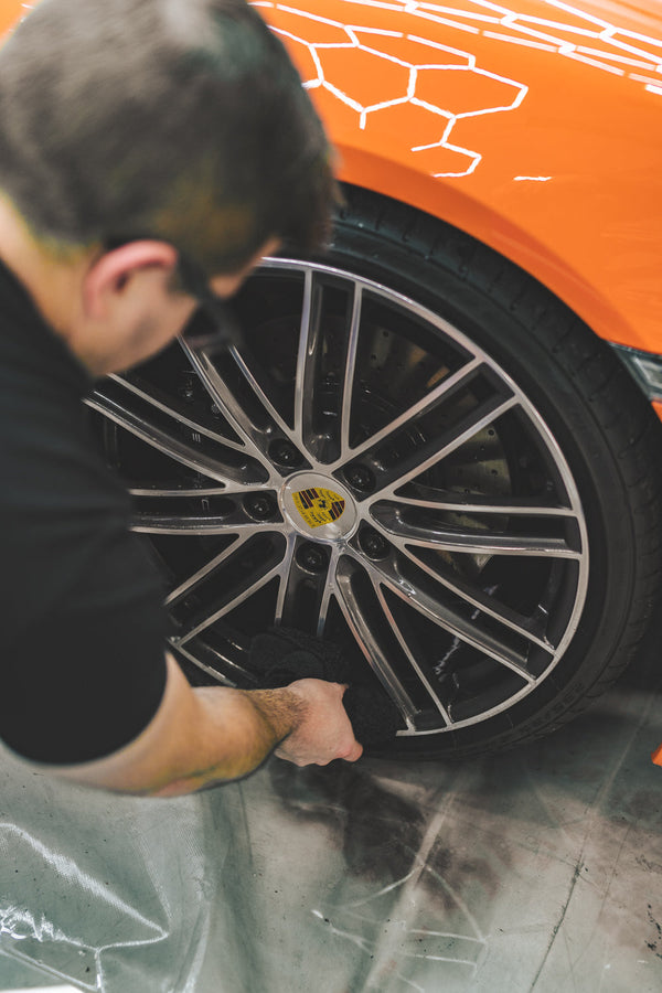 A closeup of a person cleaning a tire with a black towel.