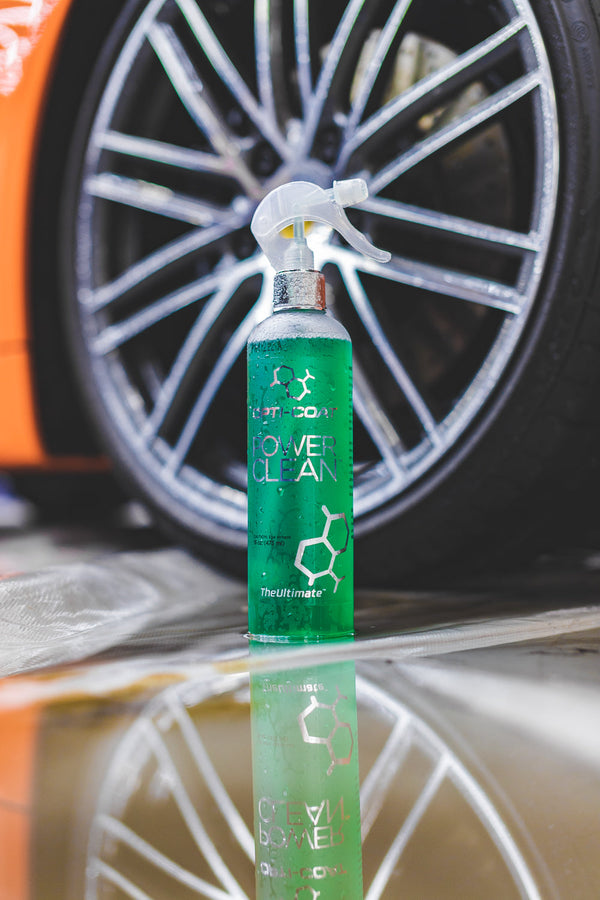 A spray bottle of Opti-Coat Power Clean in front of a wheel.