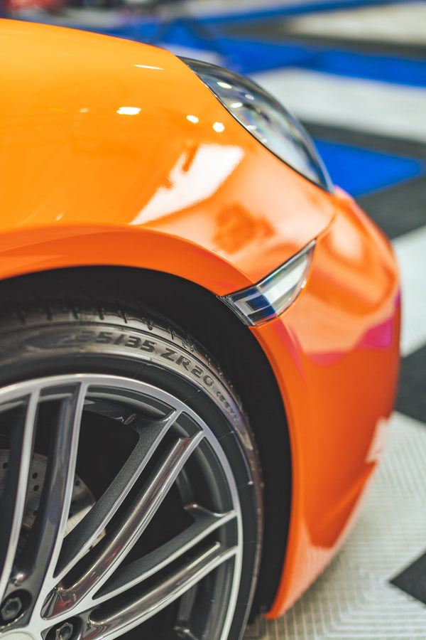 A closeup of the front of an orange car.