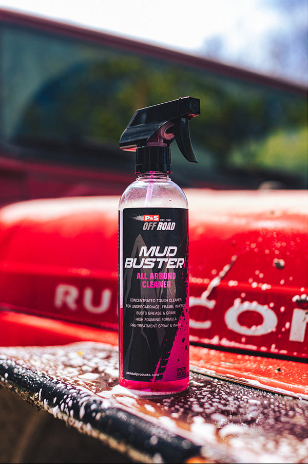 A spray bottle of P&S Mud Buster on the hood of a freshly cleaned red jeep.