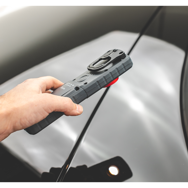 A closeup of a person holding the Sunmatch 3 over the hood of a car.