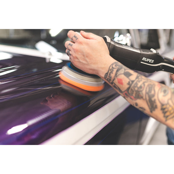 A closeup of a person polishing a purple car.