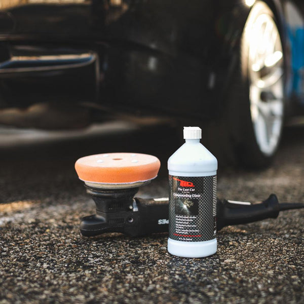 A bottle of TLD The Last Cut and polisher in front of vehicle.