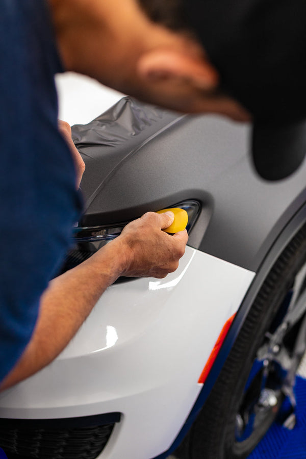 A person using the Yelloplek on a car headlight.