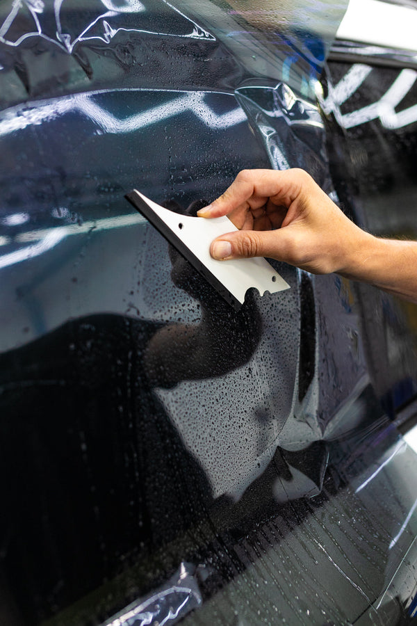 A person using a Yellotools YelloFlex Shape on a black car door.