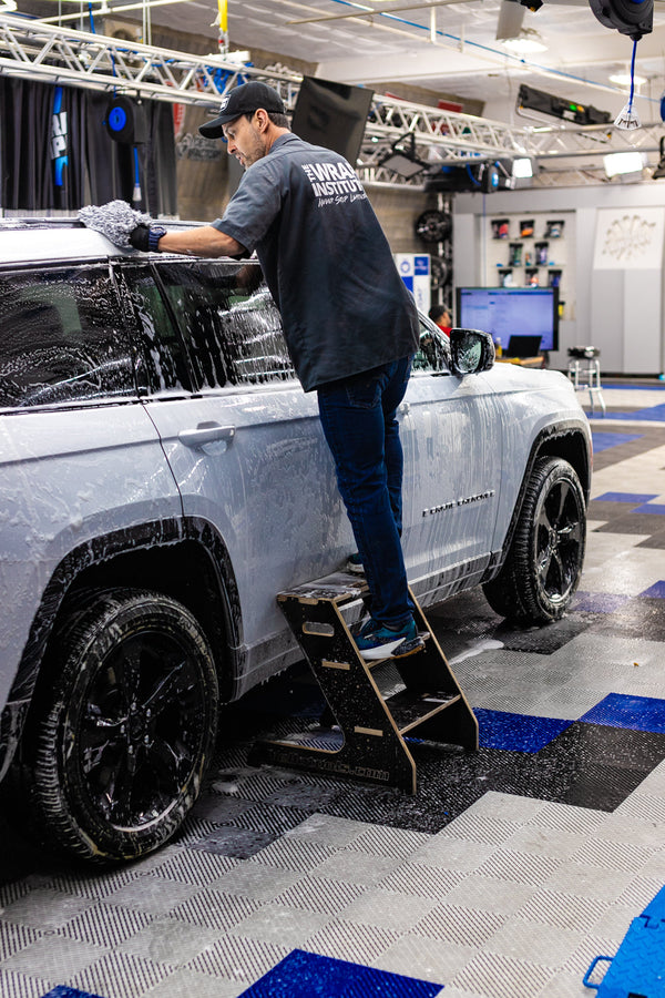 A person using a three step Wrap Step and TRC Mitt to clean the top of a light blue Jeep Cherokee.